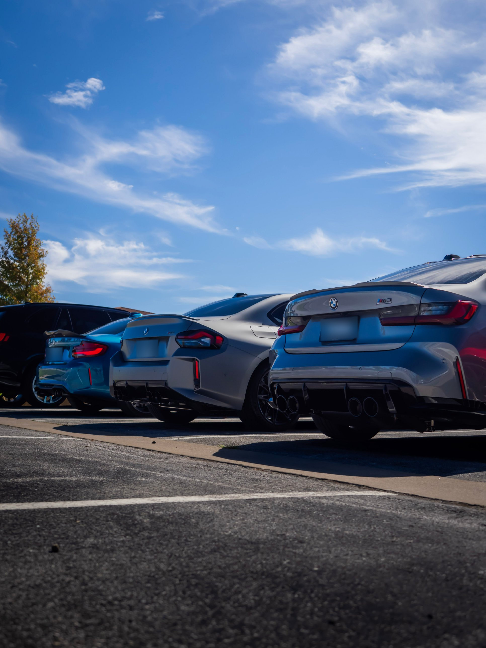 A row of performance cars parked under a blue Arkansas sky, seen from behind at ground level.